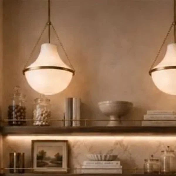 Aged brass pendants over a lit marble backsplash